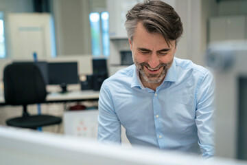 Happy mature businessman at desk in office