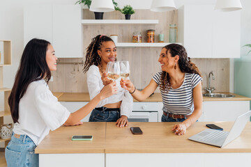 Happy roommates toasting wineglasses in kitchen at home