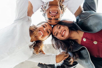 Happy young multiracial friends huddling together