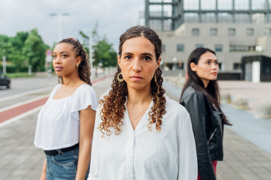 Confident Woman Standing In Front Of Friends On Footpath