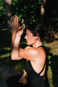 Yoga teacher with eyes closed exercising vajrasana garudasana posture in park