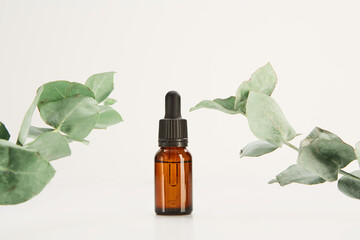 Glass dropper vial mockup decorated with plants on white.