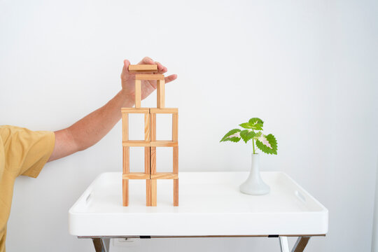 Hand of man building wooden block tower on table