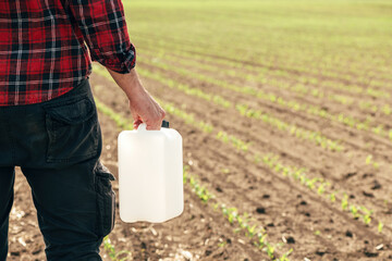 Corn crop protection concept, male farmer agronomist holding jerry can container canister with...