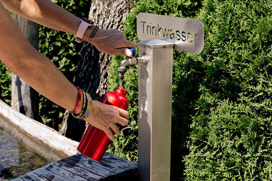 Hands of woman filling water in bottle from drinking fountain