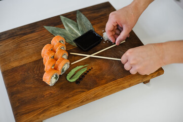 close up of delicious sushi with chopsticks and salmon on wooden cutting board