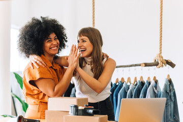 Cheerful online store owners high-fiving each other in their thrift store