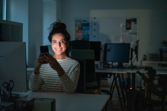 Smiling businesswoman with mobile phone at desk in office