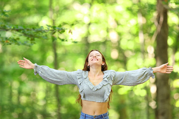 Excited woman celebrating vacation in a green forest