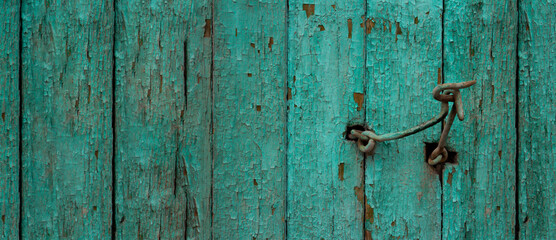 Banner with wooden green old fence with peeling paint. Hook for closing the door. Place for text. The concept of devastation, old age and destruction of the old world. Closing borders. Copyspace