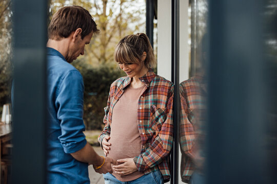 Man looking at pregnant stomach of woman