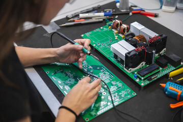 Engineer soldering mother board on table in workshop