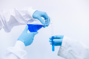 Scientist pouring blue liquid in test tube at laboratory
