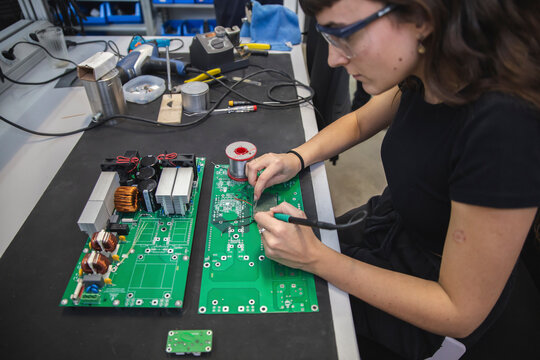 Technician soldering mother board in electronics industry