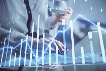 Double exposure of businesswoman hands typing on computer and financial graph hologram drawing. Stock market analysis concept.