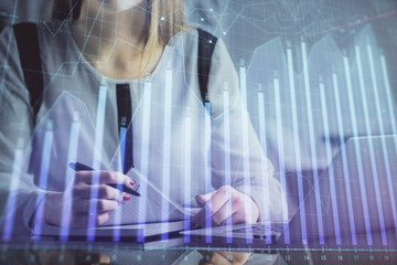 Double exposure of businesswoman hands typing on computer and financial graph hologram drawing. Stock market analysis concept.