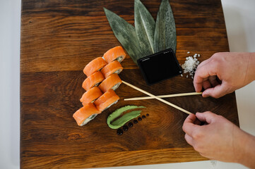 sushi rolls with salmon and chopsticks on wooden table, closeup