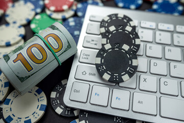 poker chips for poker with banknotes twisted placed on laptop keyboard.