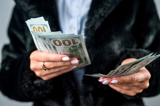 large sum of dollars close up in the beautiful young hands of a woman who has become rich.