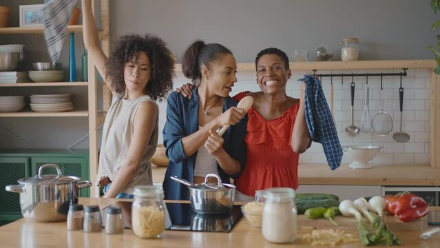 Beautiful young women spending time together and having fun. Latin and hispanic girls lifestyle moments in the kitchen while cooking. Representation of happy friends laughing and sharing good vibes