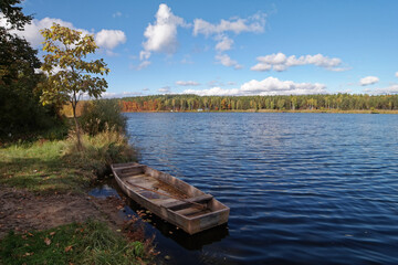 Widok na jezioro i łódkę w jesiennej odsłonie.  © Adam Sadlak