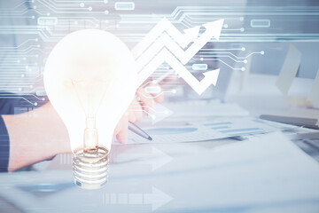 Double exposure of man's hands holding and using a digital device and bulb hologram drawing. Idea concept.