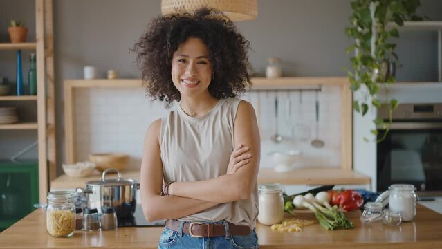 Happy young latin woman smiling at camera in her kitchen. Concept about lifestyle, carefee and successful women