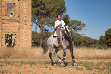 Beautiful young woman performing cowboy dressage exercises, riding her horse in the countryside on...