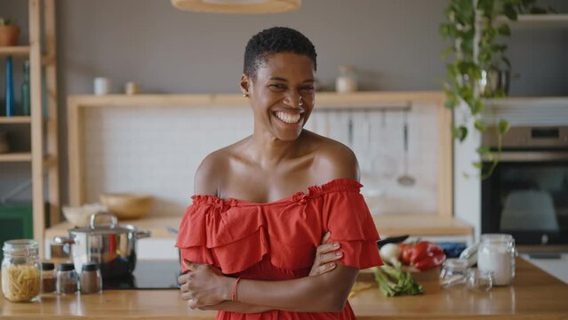 Happy young latin woman smiling at camera in her kitchen. Concept about lifestyle, carefee and successful women
