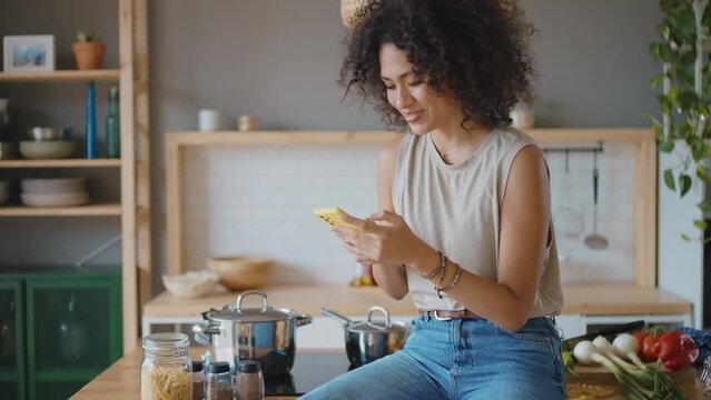 Happy young latin woman smiling at camera in her kitchen. Concept about lifestyle, carefee and successful women