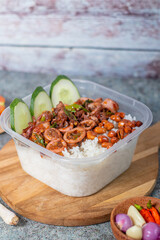 Rice with side dishes of squid and cucumber added with peanuts served on a wooden board