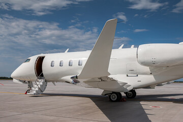 Close-up modern white private jet with an opened gangway door at the airport apron