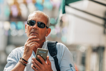 tourist man with backpack and mobile phone on the street looking for an address