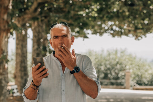 man smoking with mobile phone outside - Powered by Adobe