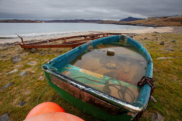 Fishing boat on Melness beach filled with rain water