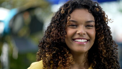 Portrait of a happy black millennial girl standing outdoors smiling. A Brazilian hispanic African American young woman with curly hair