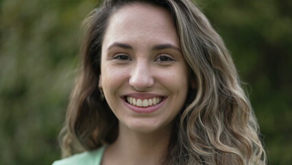 Joyful hispanic latina girl standing outside smiling. Young woman latina portrait. Millennial 20s female person in tracking shot