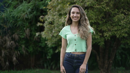Joyful hispanic latina girl standing outside smiling. Young woman latina portrait. Millennial 20s female person in tracking shot
