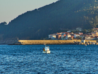 Unrecognisable fishermen fishing on the boat in the Galician estuary at sunset