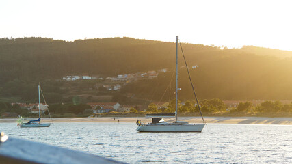 View from the sea of sailboats in the water and people walking on the beach