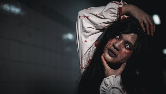 Happy halloween day concept. Screaming zombie female face with blood grabs her head to twist it off, Horror bloodthirsty woman ghost or zombie she is horror scary with breaks her neck at dark night