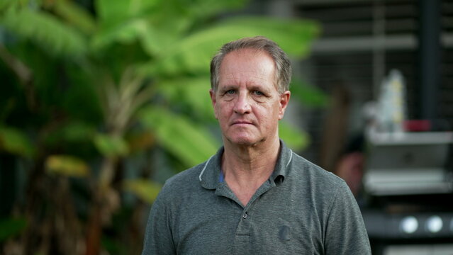 Portrait Of An Older Man With Serious Expression Standing Outdoors Looking At Camera. Closeup Senior Male Face