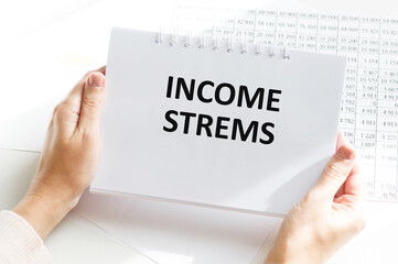 income streams text on a notebook in the hands of a businessman on the background of a desktop