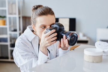 Side view portrait of young woman taking product images of handmade beauty cream with professional...