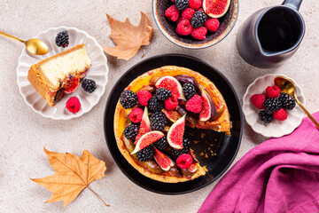 Homemade cheesecake with autumn fruits: figs, strawberries and blackberries. Breakfast table with dried leaves. Thanks giving day.