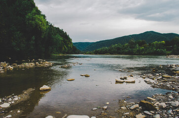 mountain river between sheer cliffs . blue clear water of the river. Young green leaves of trees