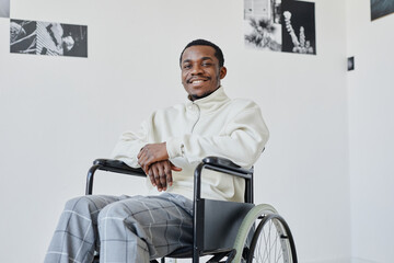 Minimal portrait of smiling black man using wheelchair while visiting modern art gallery, copy space