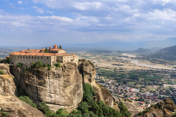 Fototapeta na wymiar Medieval Christian Holy Monastery of St. Stephen lies on the south-facing slope cliff of the Andikhasia Mountains in the upper valley of curly Pinios River, Kalabaka, Meteora, Greece