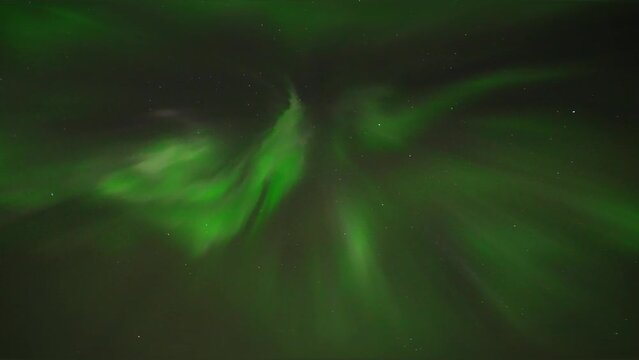 Bottom up shot of flickering green northern lights at night sky in Iceland - handheld panning