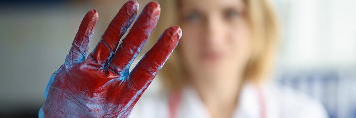 Doctor showing stop gesture with gloved hand with blood closeup